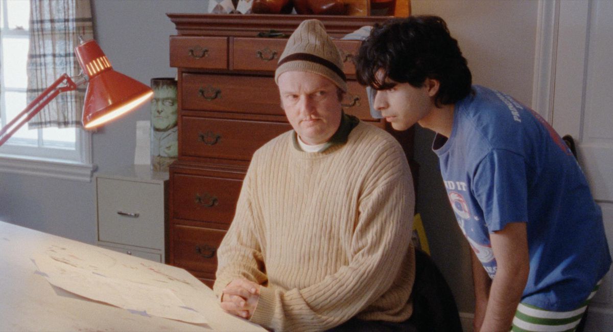 Robert (Daniel Zolghardi) mira por encima del hombro de Wallace (Matthew Maher) en su mesa de dibujo en Funny Pages