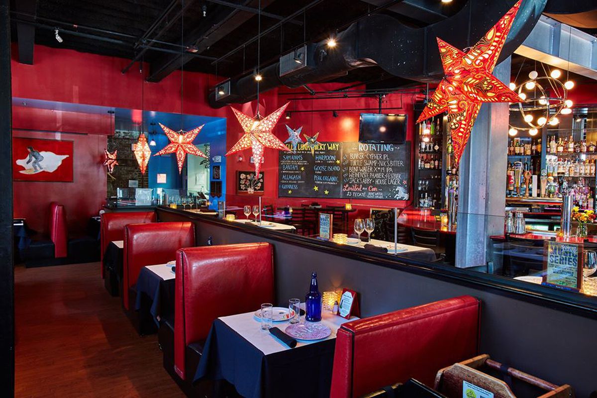 Interior restaurant and bar photo with red walls, shiny red booths, and hanging decorative star lamps (also red).