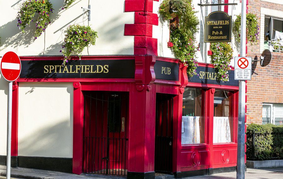 白色餐厅的外部，餐厅入口处醒目的红色边框，上面写着“斯皮塔菲尔德”和“酒吧”。