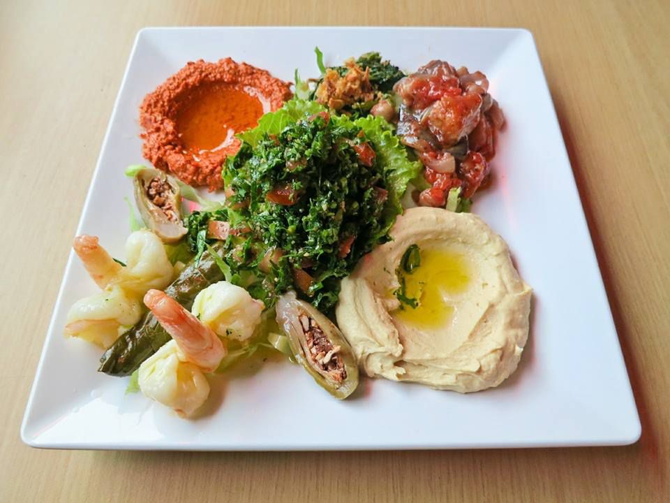 A plate comes with a dollop of tabbouli, hummus, pickled vegetables, shrimp, and muhmarra