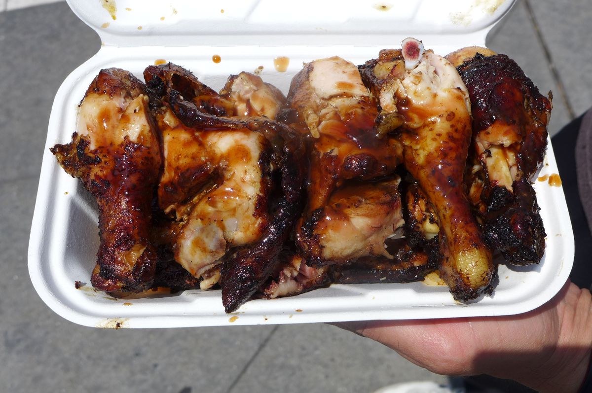 A white compartmentalized container with chicken parts lined up.
