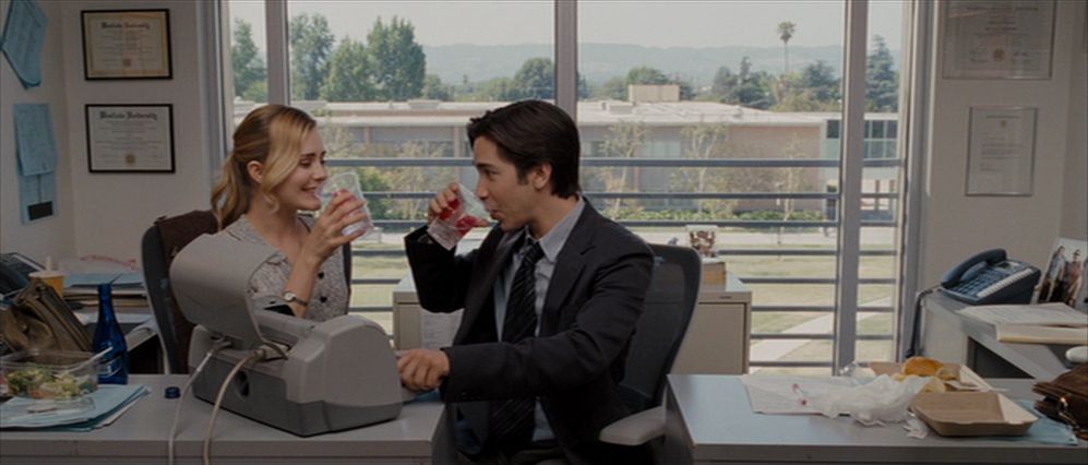 Justin Long and Alison Lohman toast behind a desk in Drag Me to Hell