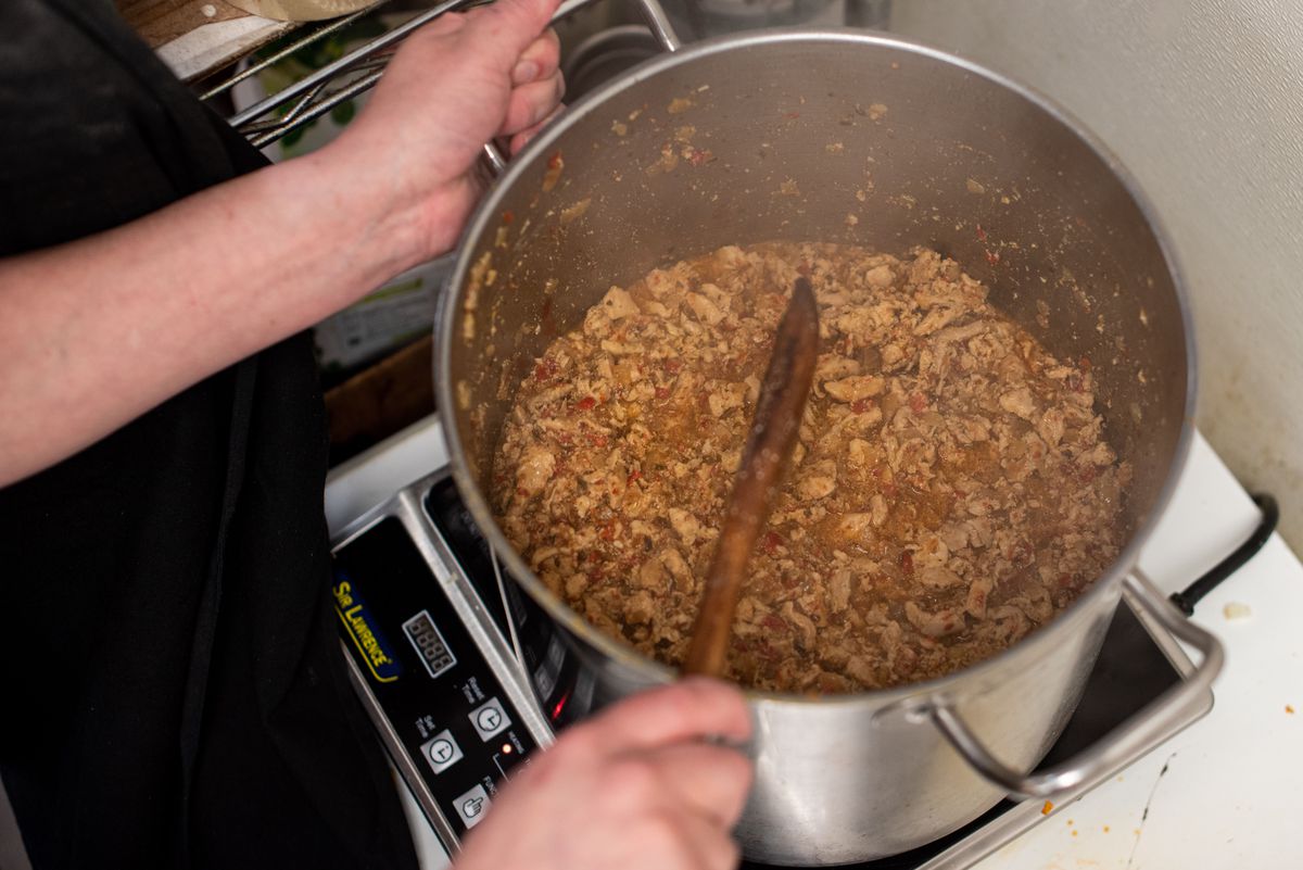 A large pan filled with ground beef being stirred with a wooden spoon.