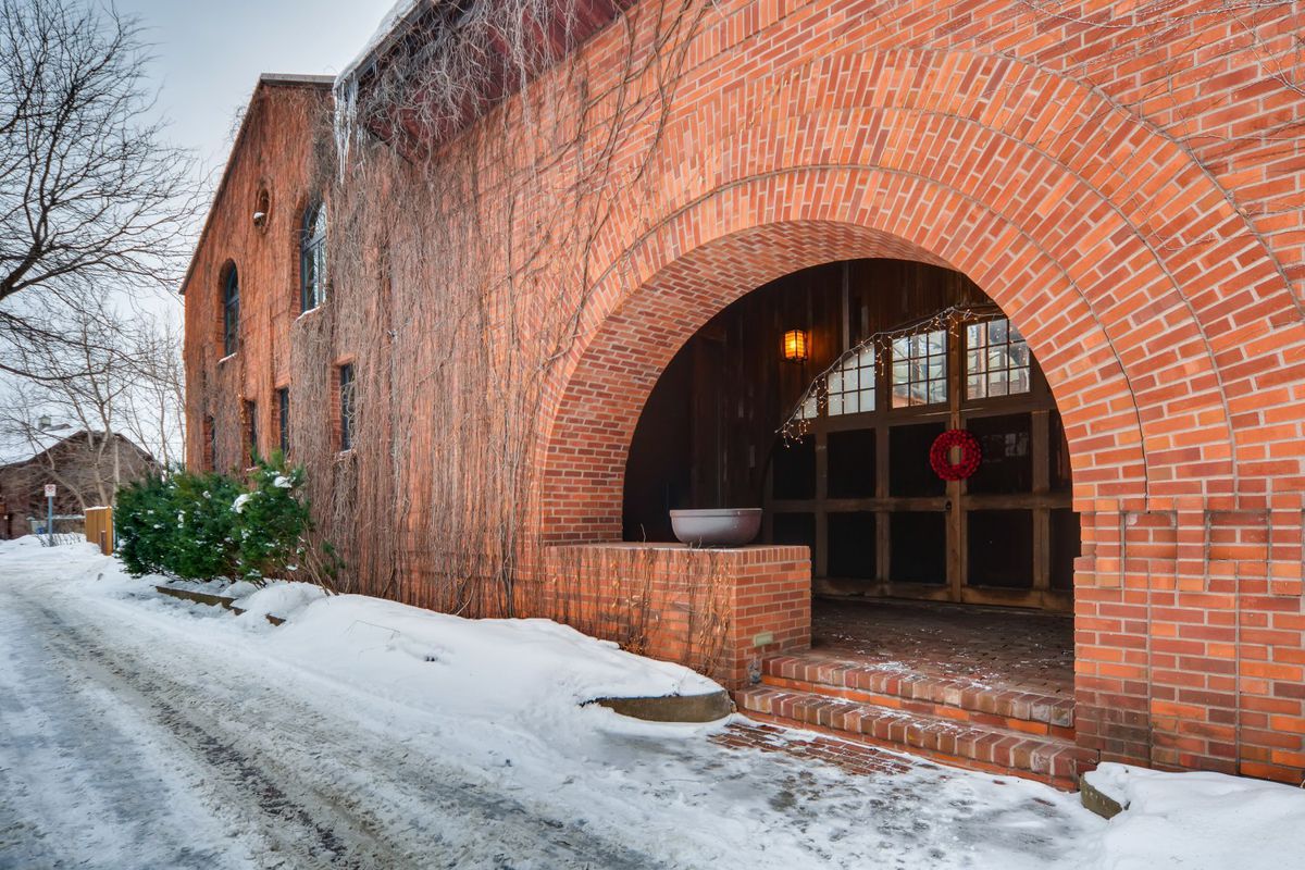 An exterior view of a brick building with an arched doorway leading to a condo. 