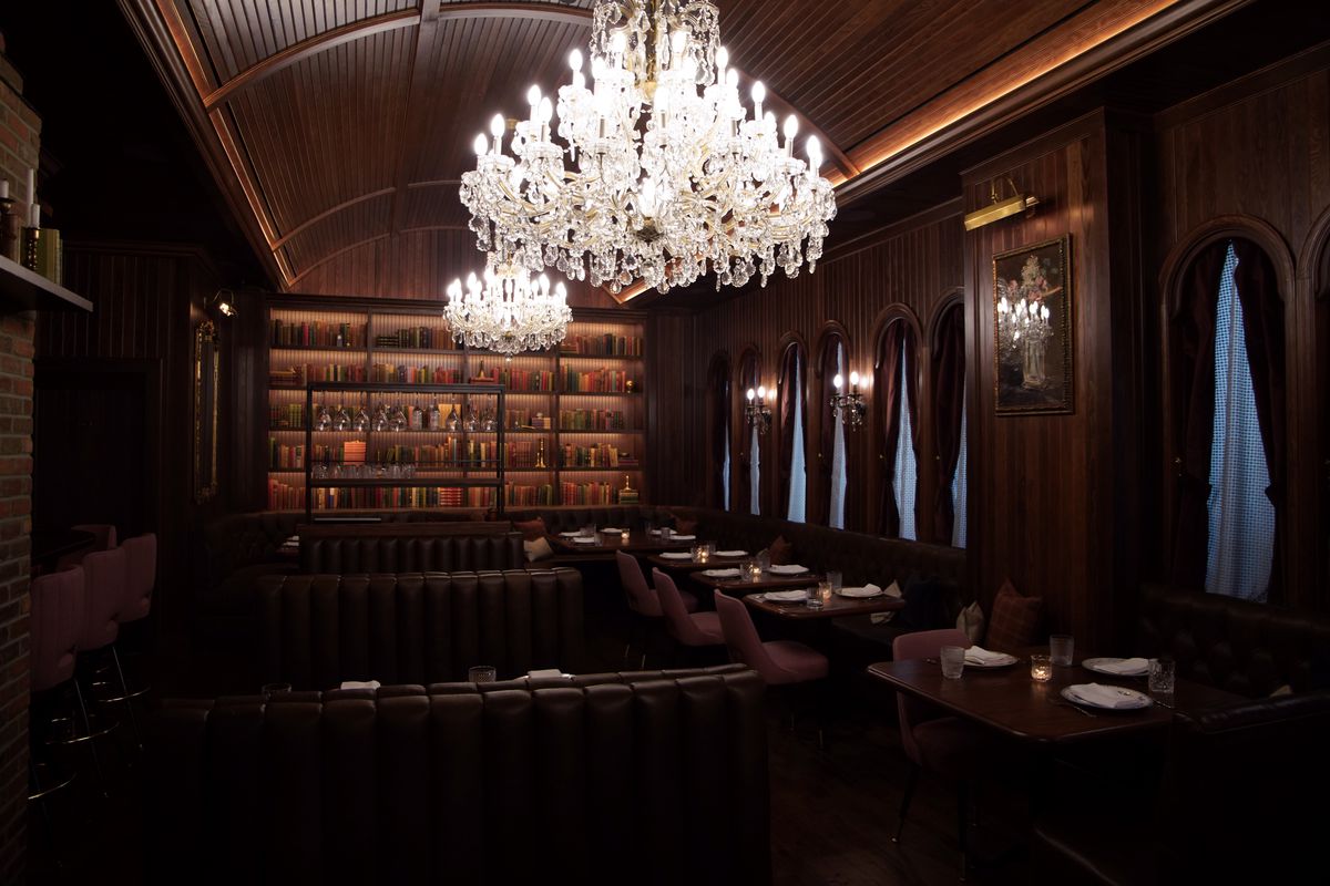 interior of restaurant with chandeliers, dark wood, library wall