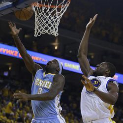 Denver Nuggets' Ty Lawson, left, lays up a shot against Golden State Warriors' Festus Ezeli (31) during the first half of Game 3 in a first-round NBA basketball playoff series on Friday, April 26, 2013, in Oakland, Calif. 