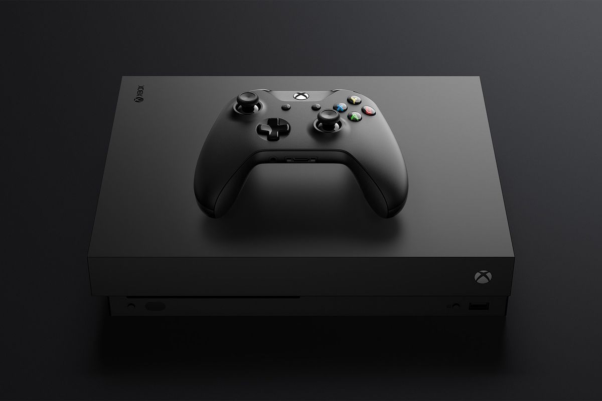 A photo of an Xbox One X console with an Xbox One controller resting on it top panel.