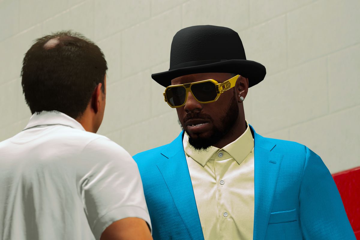 a guy in a white shirt with a bald spot on the back of his head talks to a large NBA player in flashy street clothes and garish sunglasses