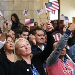 One hundred twenty-two citizenship applicants from 43 countries wave their flags after taking the oath of allegiance during a naturalization ceremony at the Capitol in Salt Lake City on Wednesday, Nov. 30, 2016.