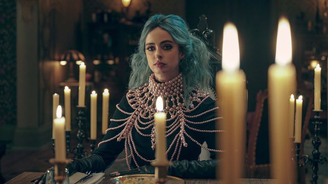 KRYSTEN RITTER as NATACHA in NIGHTBOOKS sitting behind some candles with her bright blue hair