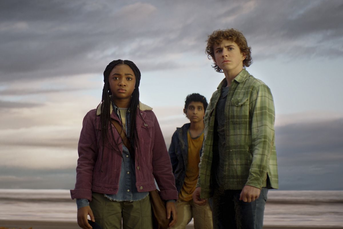 Percy (Walker Scobell), Annabeth (Leah Sava Jeffries), and Grover (Aryan Simhadri) standing on a beach