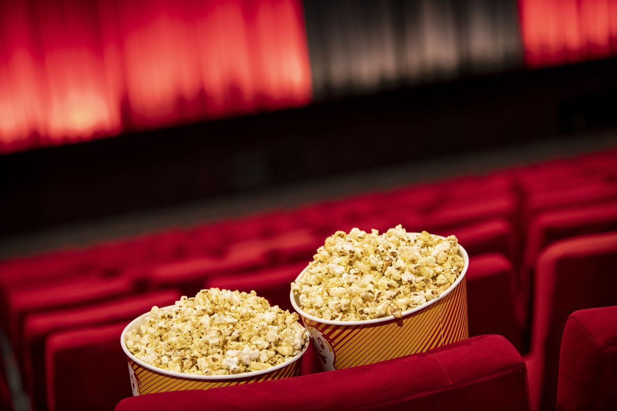 A red velvet theater seat with two popcorn containers.