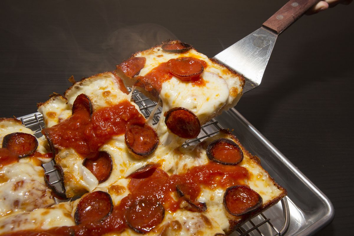 A thick Detroit-style pan pizza cut in square slices with pepperoni and tomato sauce on top.