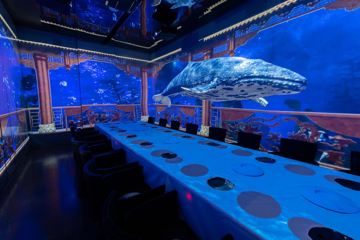 A dining room with projection lighting that displays a whale soaring over the dining table