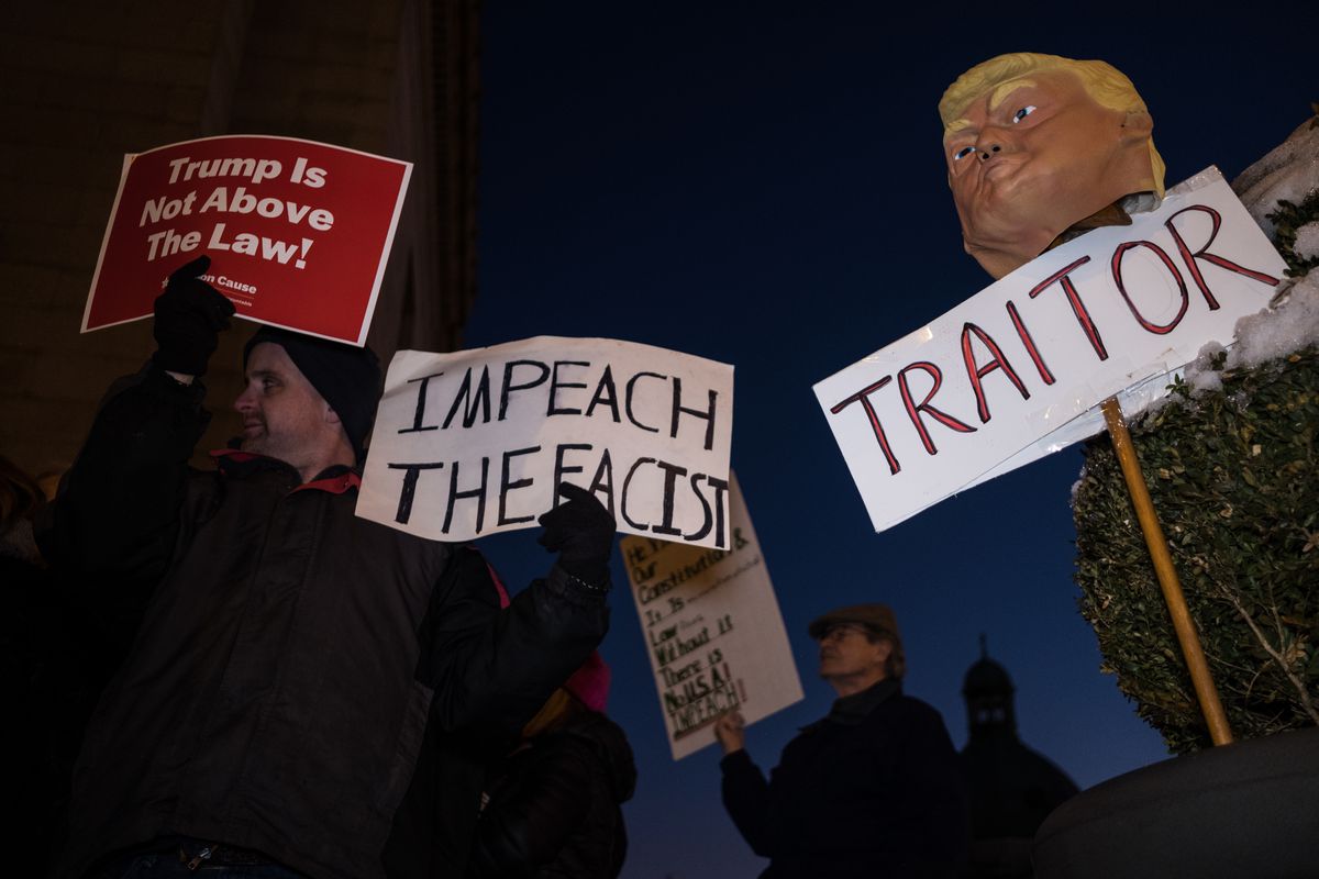Protesters hold placards that read “Trump is not above the law!” and “Impeach the fascist” and “Traitor” during a Trump pro-impeachment rally.