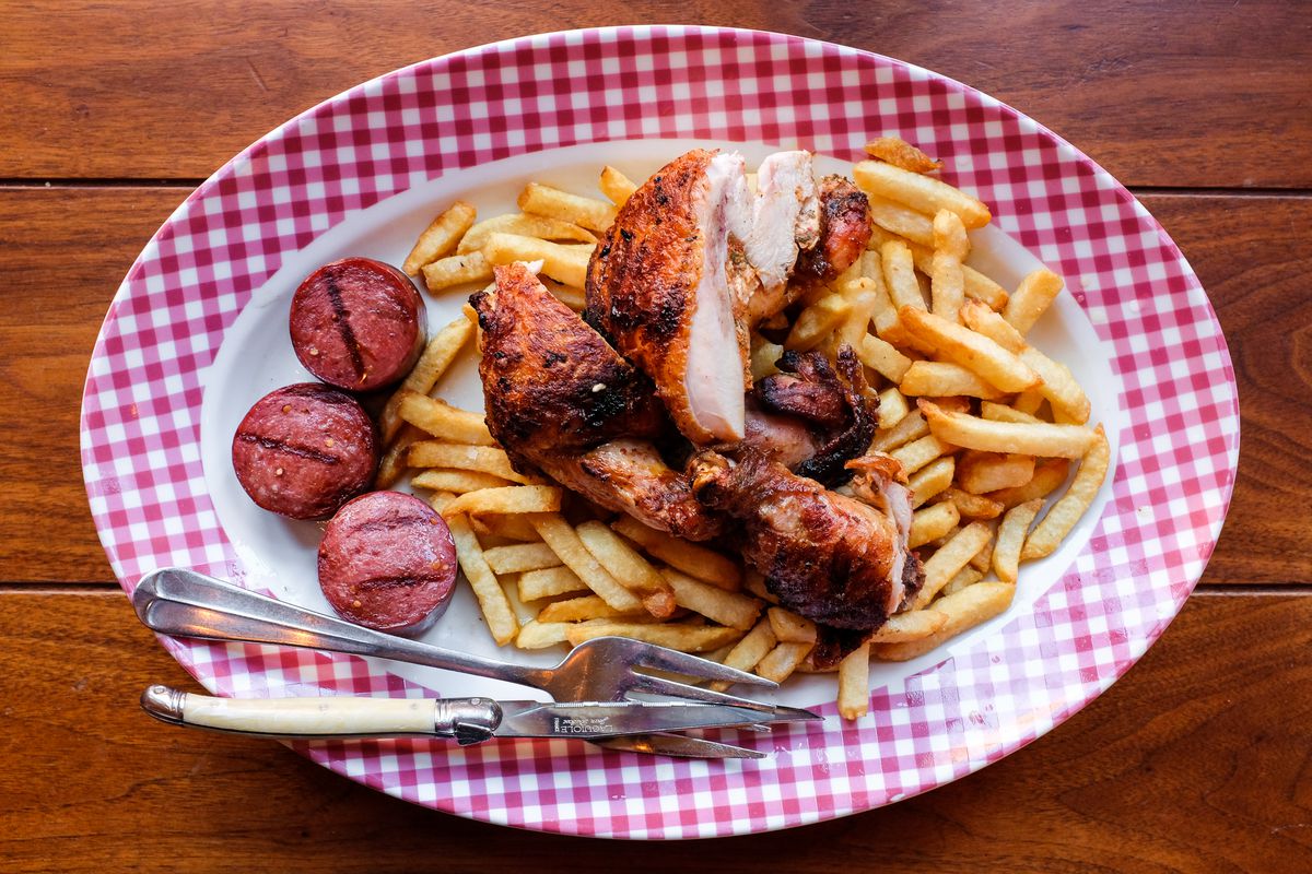 A plate with grilled chicken and slices of summer sausage, and french fries