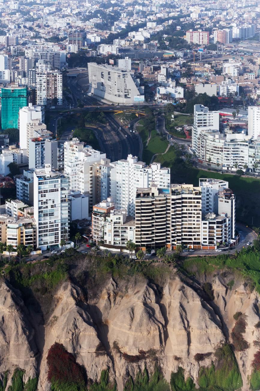 An aerial view of buildings along a ravine. A modern concrete building is in the center next to highways.