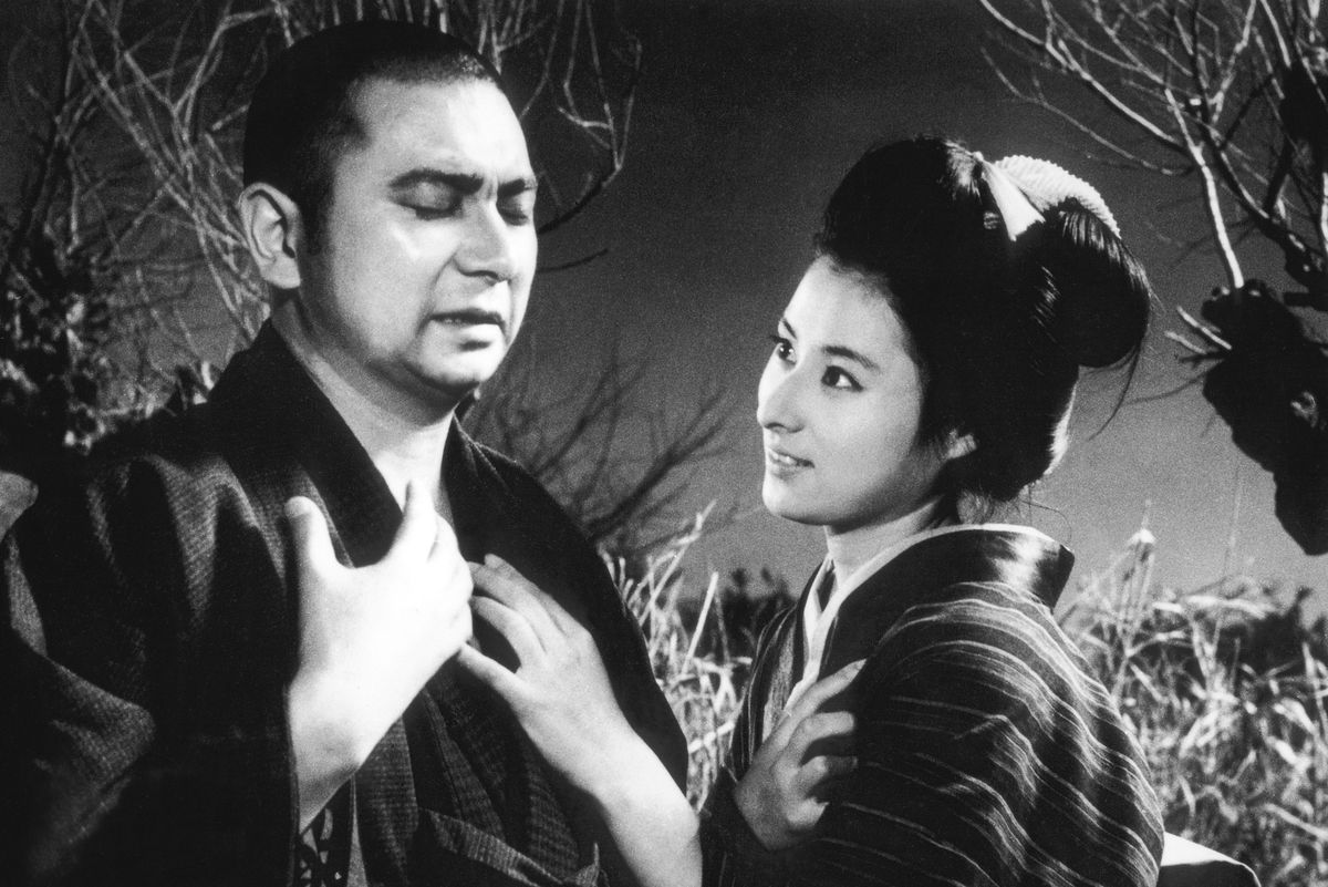 A black-and-white image of Shintaro Katsu, with his eyes closed, as Zatoichi. A young woman looks at him adoringly, as he holds both hands to his chest.