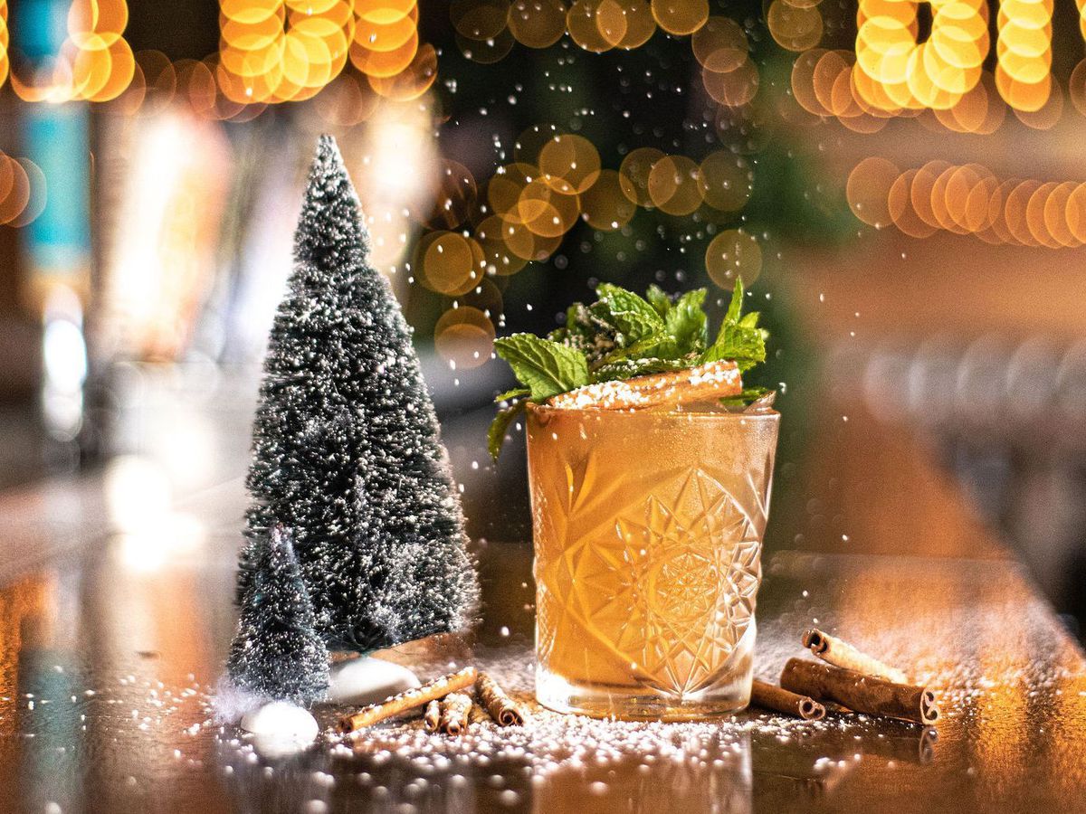 Miniature Christmas tree and a flutter of snow on the bar with a golden cocktail.  