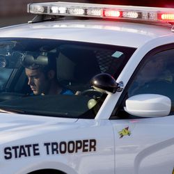 Mike Ellsworth, the brother of Utah Highway Patrol Trooper Eric Ellsworth rides in the passenger seat of Trooper Ellsworth's patrol car, driven by Lt. Lee Perry, Ellsworth's supervisor, as Ellsworth's body is transported from the State Medical Examiner's Office in Salt Lake City on Friday, Nov. 25, 2016.