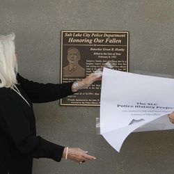 Gallivan Center director Talitha Day unveils a plaque at the Gallivan Center in memory of police detective Green B. Hamby, who was killed 92 years ago while tracking down a burglary suspect, Monday, April 29, 2013, in Salt Lake City.