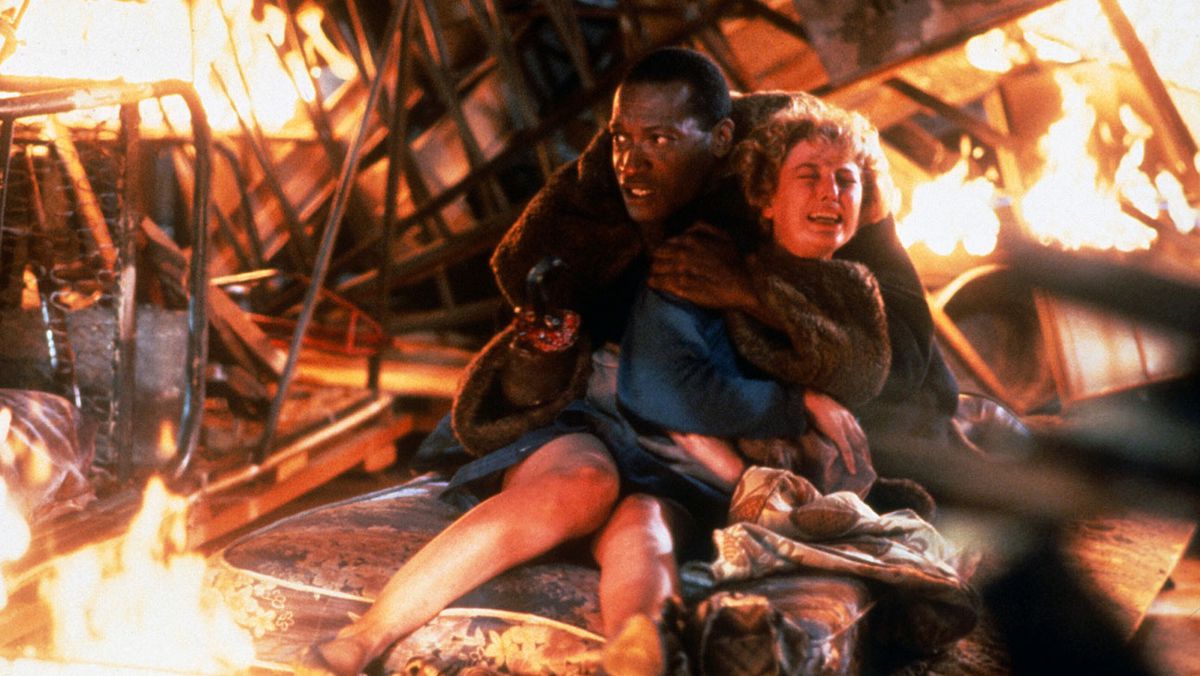 Candyman (Tony Todd) clutching Helen Lyne (Virginia Madsen) amid the burning wreckage of a bonfire in Candyman (1992)