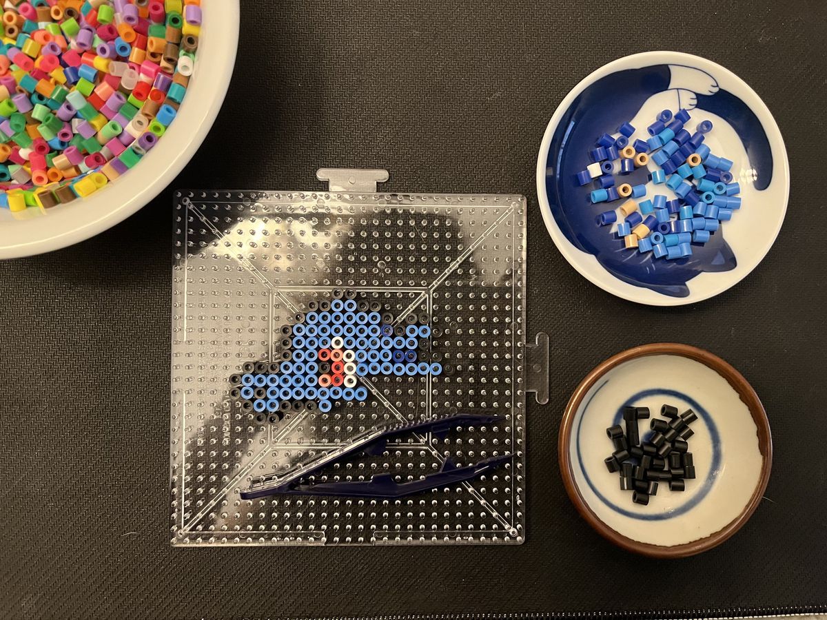 a top down photo of a half-finished horsea perseal bead creation. the beads are arranged on a clear peg board.