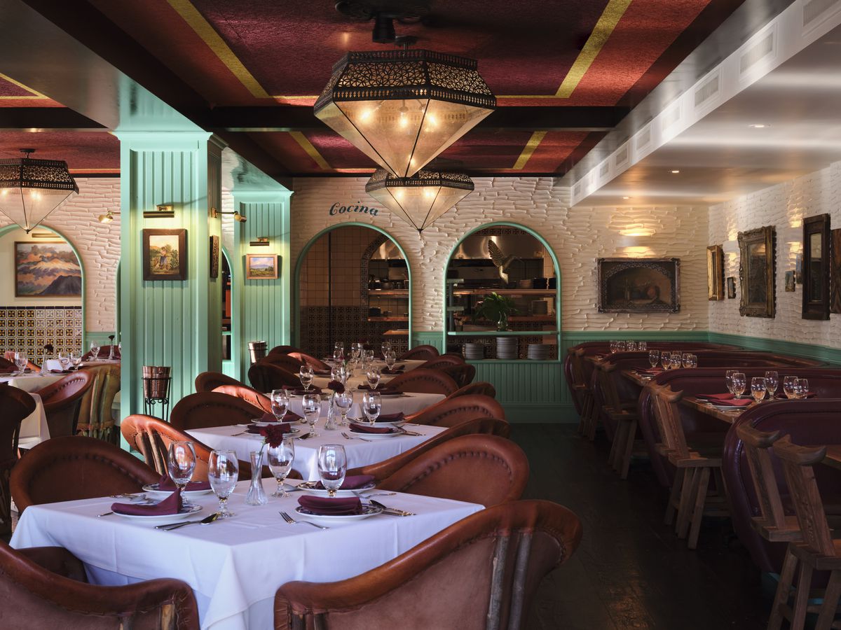 白色和蓝绿色的餐厅外观，有拱形门框，瓷砖墙壁和大吊灯。