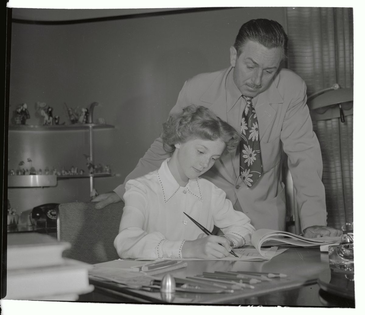 In an undated archival photo, Walt Disney leans over a desk where actor Kathryn Beaumont, the voice and live-action reference for&nbsp;Alice&nbsp;in Disney’s Alice in Wonderland and for Wendy Darling in Disney’s Peter Pan, signs a contract