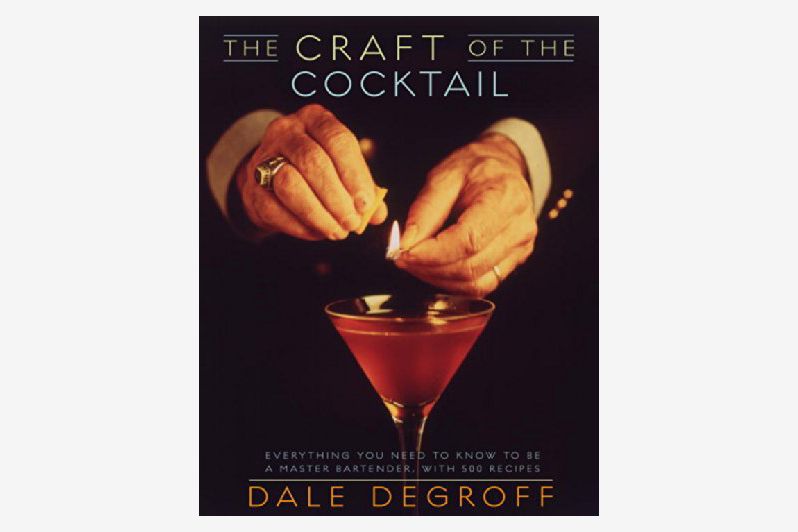 The cover of “The Craft of the Cocktail” book with a close-up shot of someone lighting a match over a cocktail in a martini glass