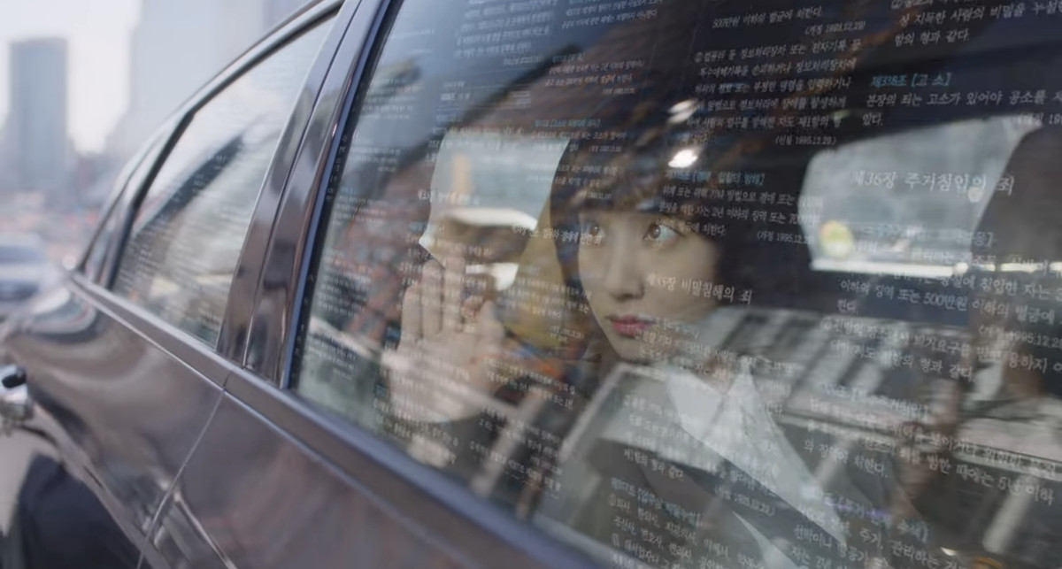 Woo Young-woo imagining facts projected against a car window, she’s reaching out to touch them