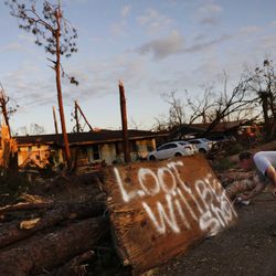 Ron Hyatt spray paints a message to warn off looters outside his damaged home from Hurricane Michael in Callaway, Fla., Sunday, Oct. 14, 2018. (AP Photo/David Goldman)