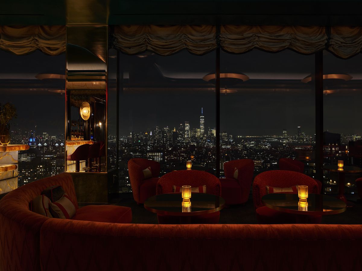 The Manhattan skyline is visible from a cocktail bar with velvet chairs and booths.