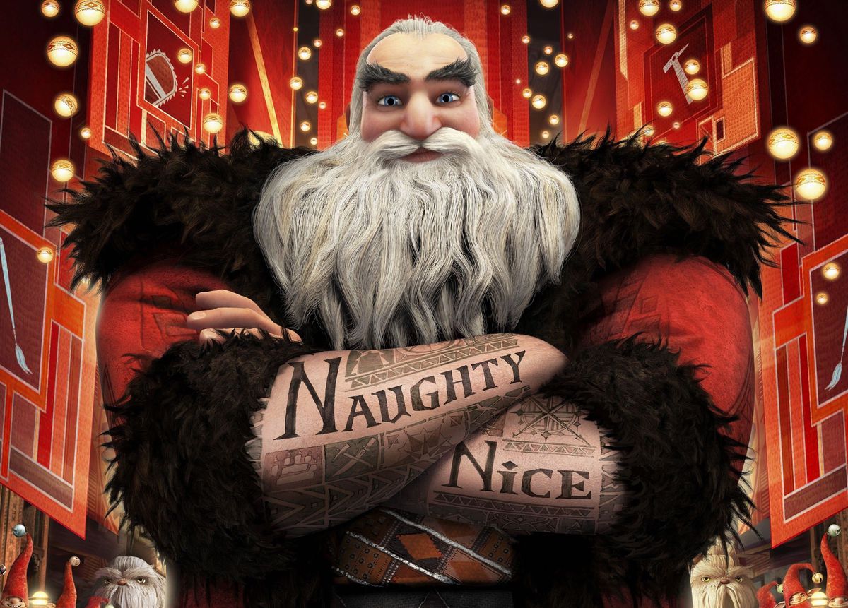 A tall, slightly smiling, muscular Santa Claus from The Rise of the Guardians stands with his arms crossed, facing the camera, elaborate tattoos reading “Naughty” and “Nice” shown on his forearms