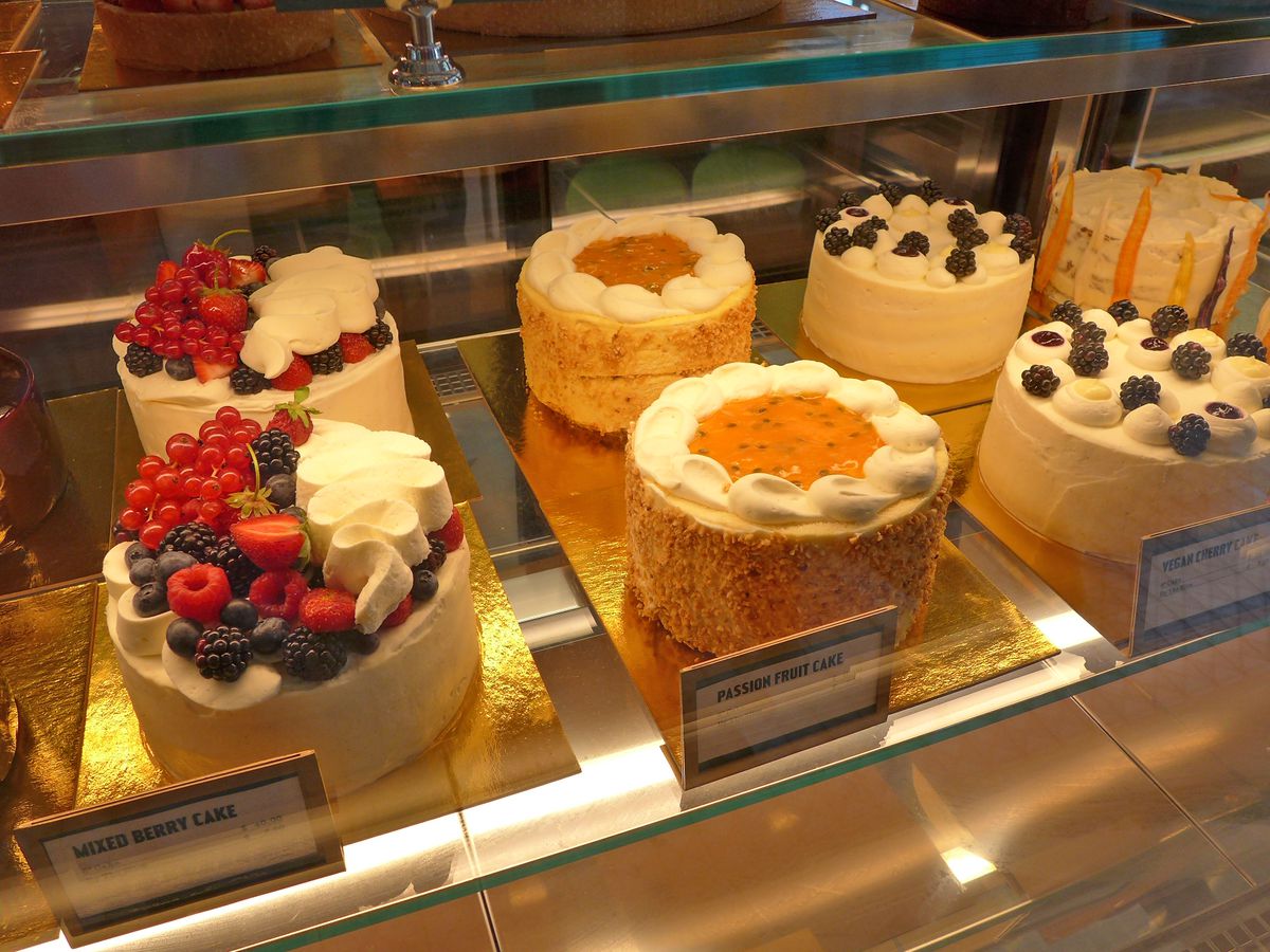 A selection of colorful fruit topped layer cakes.