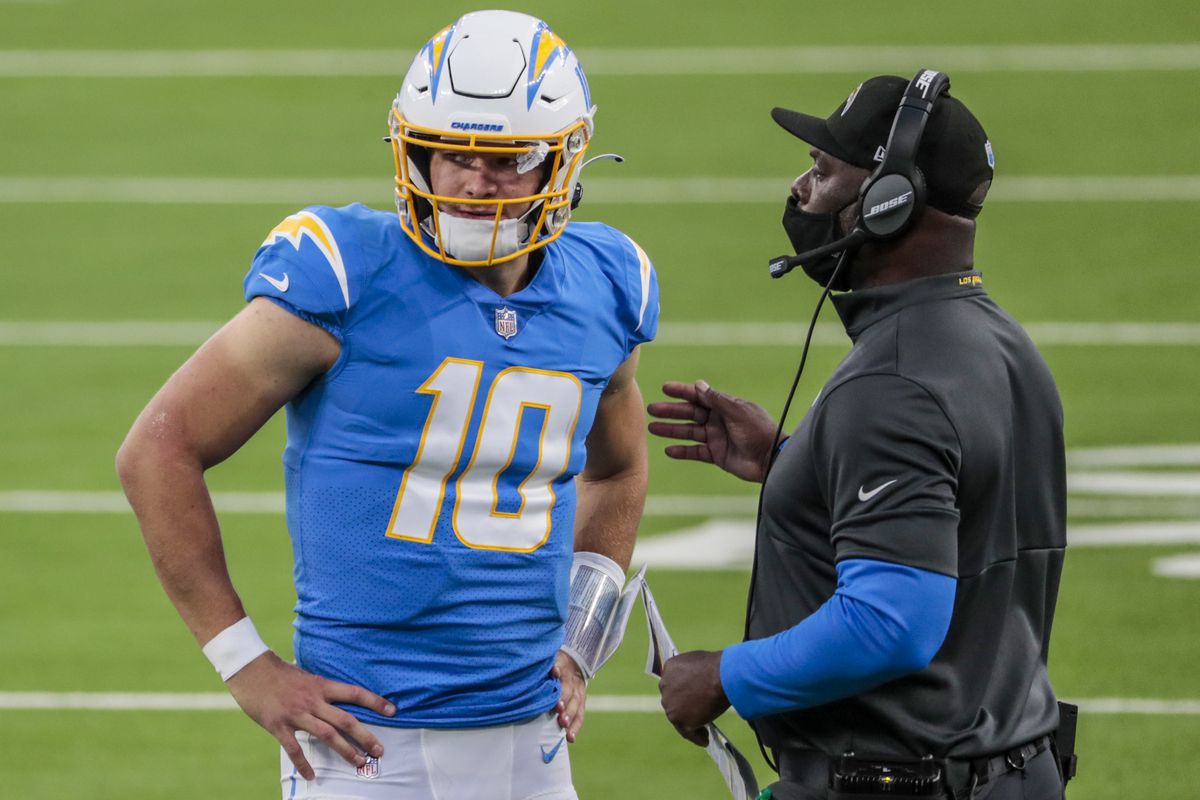 Los Angeles Chargers quarterback Justin Herbert (10) and head coach Anthony Lynn talk before executing a third down play during a last minute drive against the Broncos at SoFi Stadium.