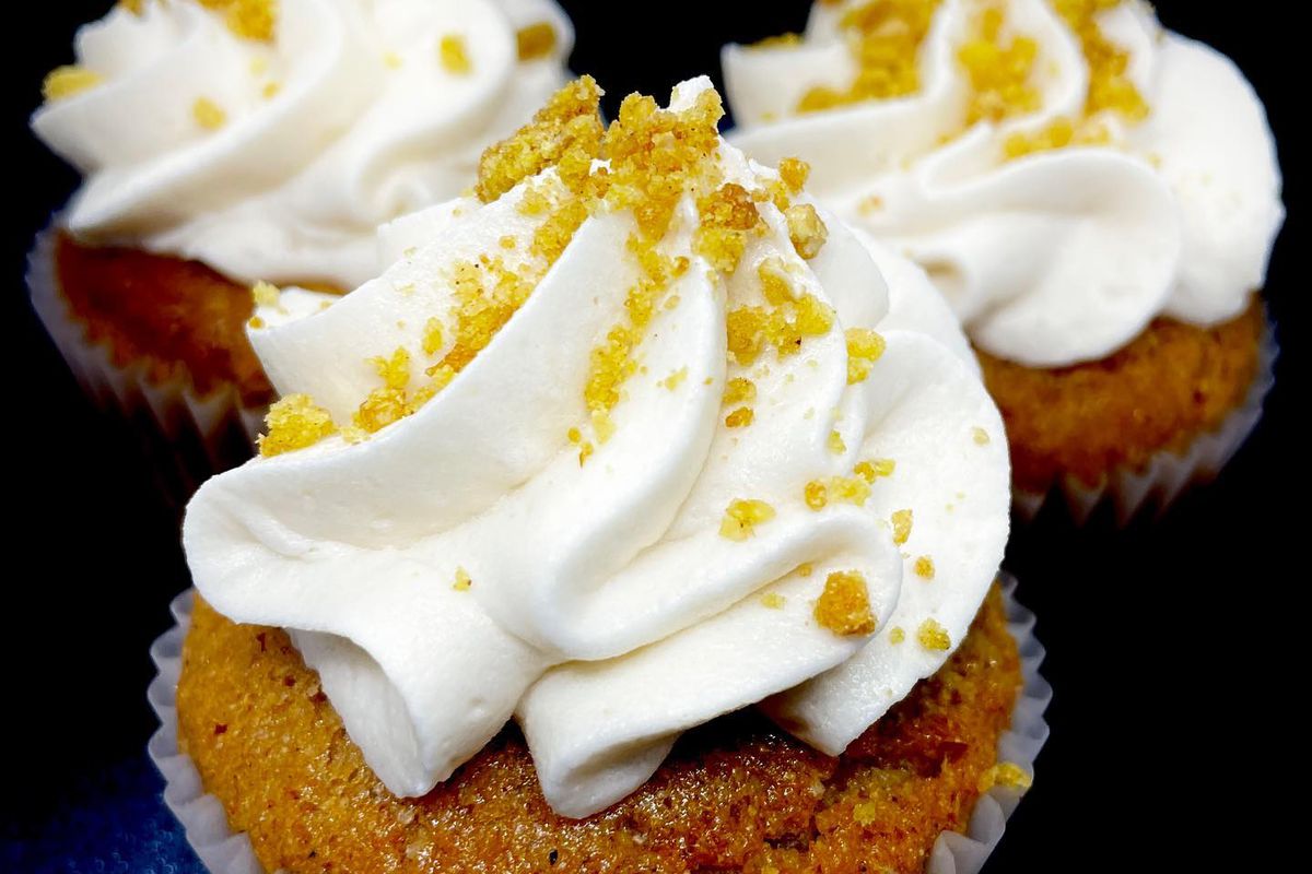 Three brown cupcakes with white frosting and yellow crumbles.