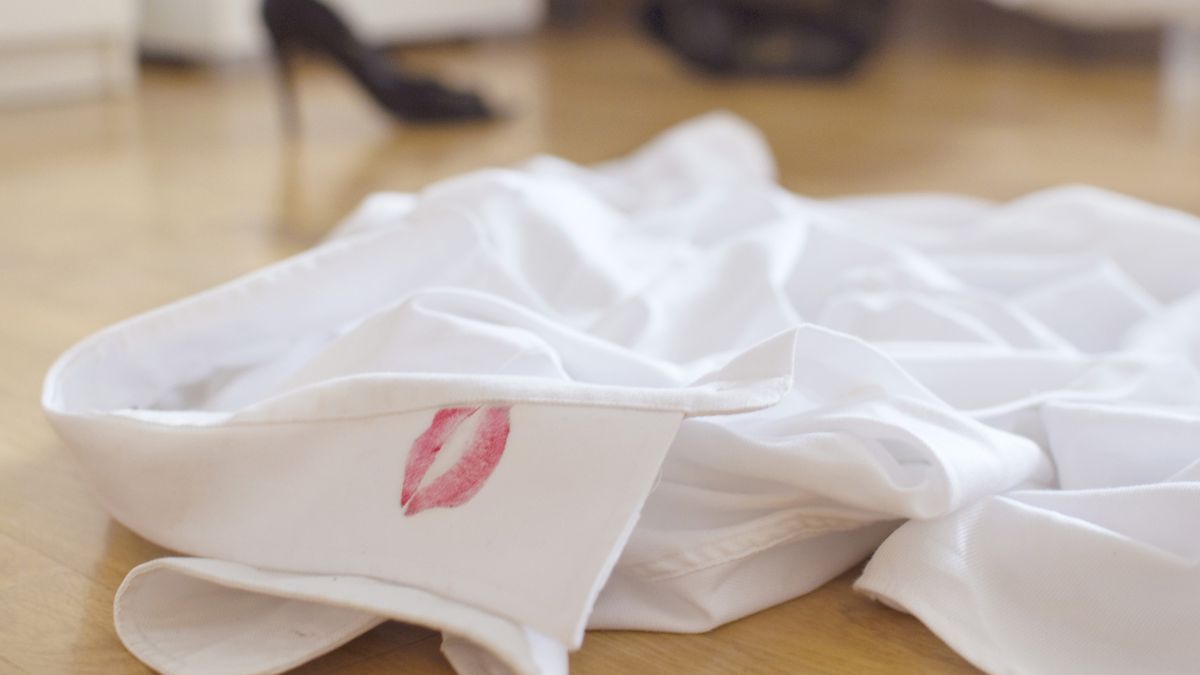 A white shirt on the floor with a red lipstick print on the collar.