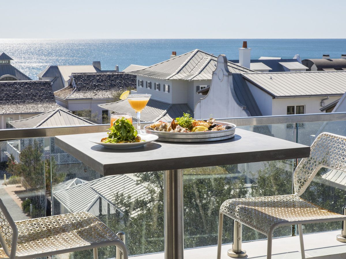 A rooftop table overlooks houses and beyond them, the Gulf Coast.