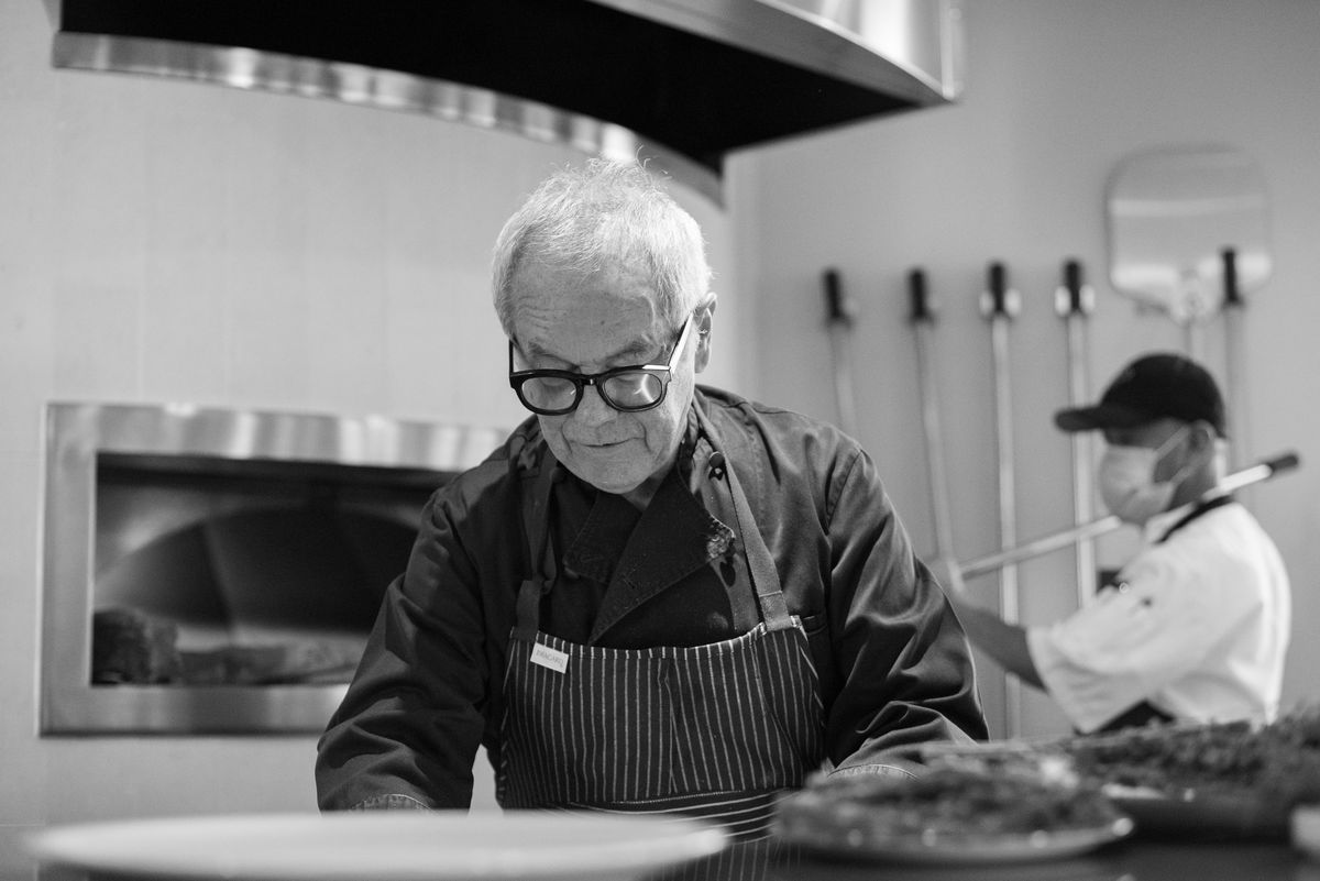 Wolfgang Puck prepares a pizza in black and white.