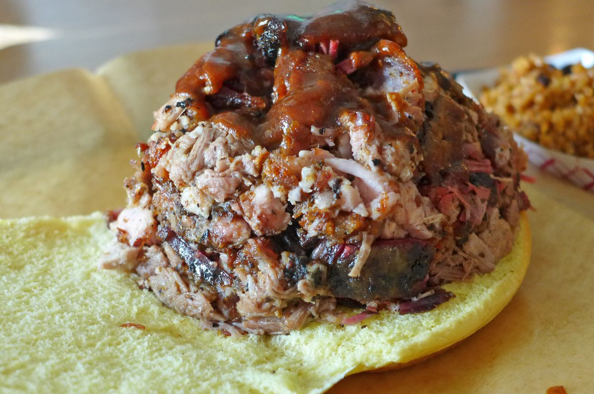 A bun spread open with a heap of chopped barbecue on top.