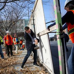 Steve Starks, president of Larry H. Miller Sports and Entertainment, helps crews from Okland Construction, including a number of individuals who are homeless, tear down a wooden fence and replace it with a metal fence at the Road Home in Salt Lake City on Friday, Dec. 1, 2017.