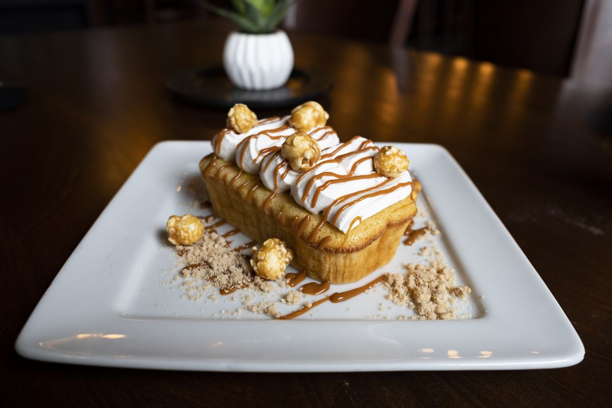 A cornbread dessert with whipped cream, crushed mazapan, and caramel popcorn toppings.