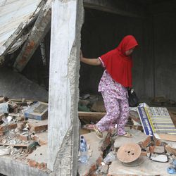Earthquake survivor Fakriyah tries to balance herself as she walks on the rubble at her shop damaged during Wednesday's earthquake in Tringgading, Aceh province, Indonesia, Friday, Dec. 9, 2016. Over a hundred people were killed in the quake that hit the northeast of the province on Sumatra before dawn Wednesday. Hundreds of people were injured and thousands buildings destroyed or heavily damaged. 