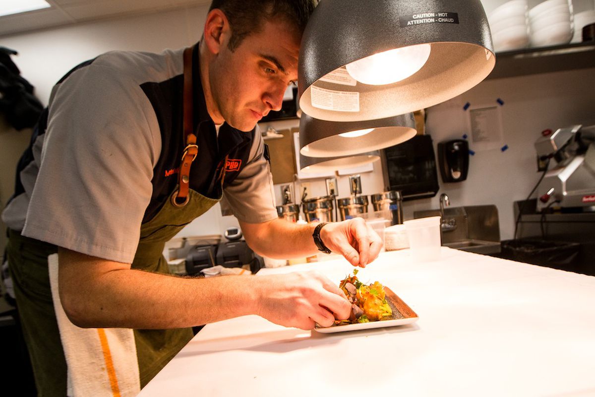 Chef Michael Gulotta leans over a dish on the line at MoPho to put on finishing touches.