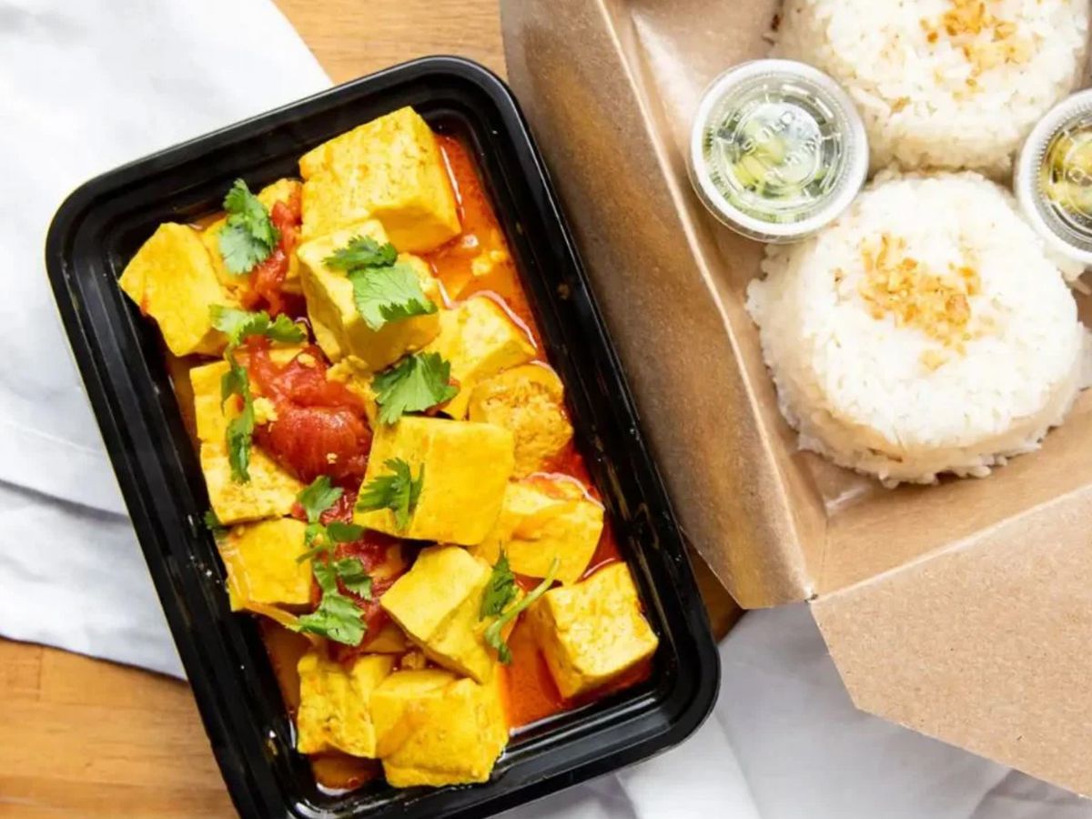 A picture of tofu curry and coconut rice in takeout containers from Top Burmese