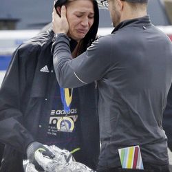 An unidentified Boston Marathon runner is comforted as she cries in the aftermath of two blasts which exploded near the finish line of the Boston Marathon in Boston, Monday, April 15, 2013. 