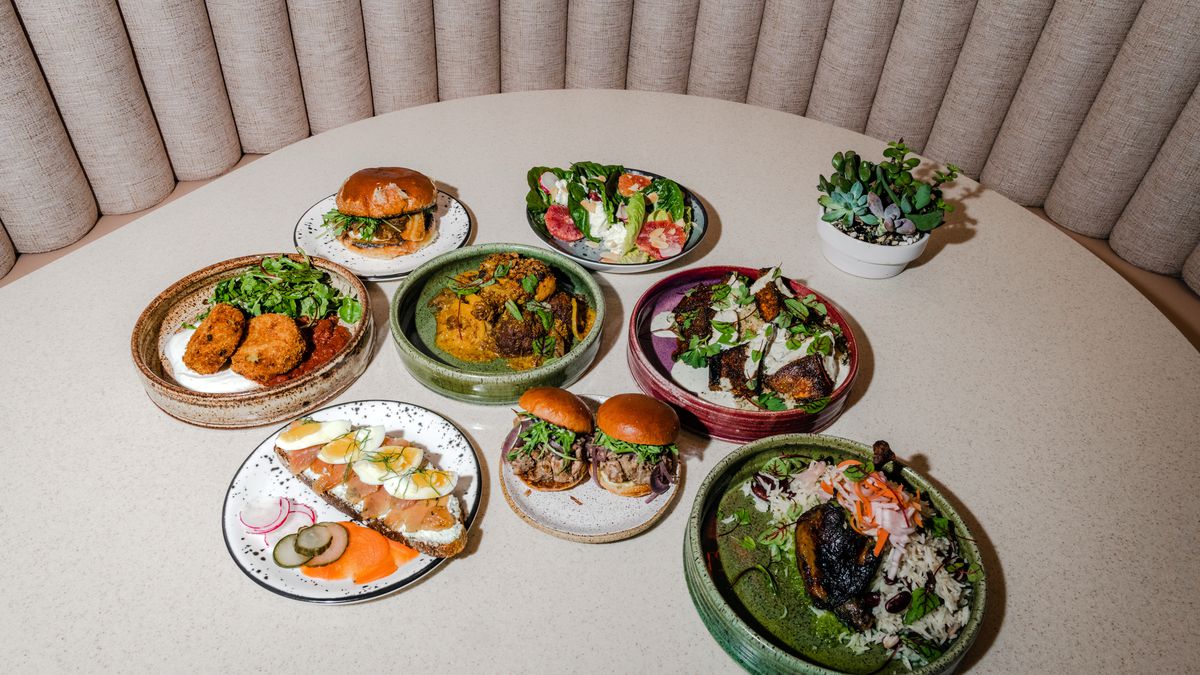 Eight colorful plates filled with food and arranged on a beige table.