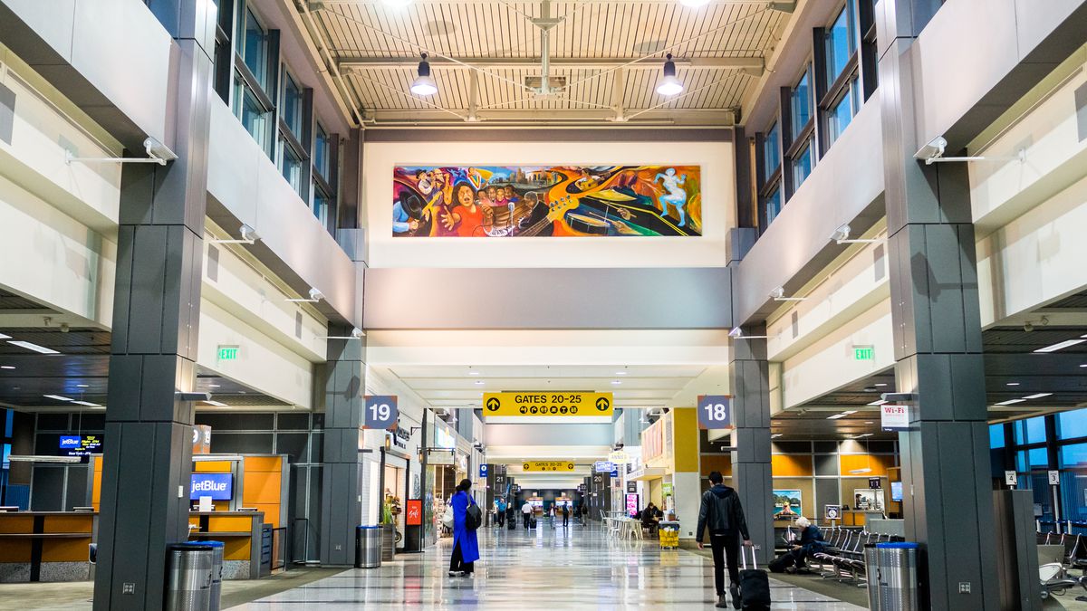 An airport terminal with art and gates. 