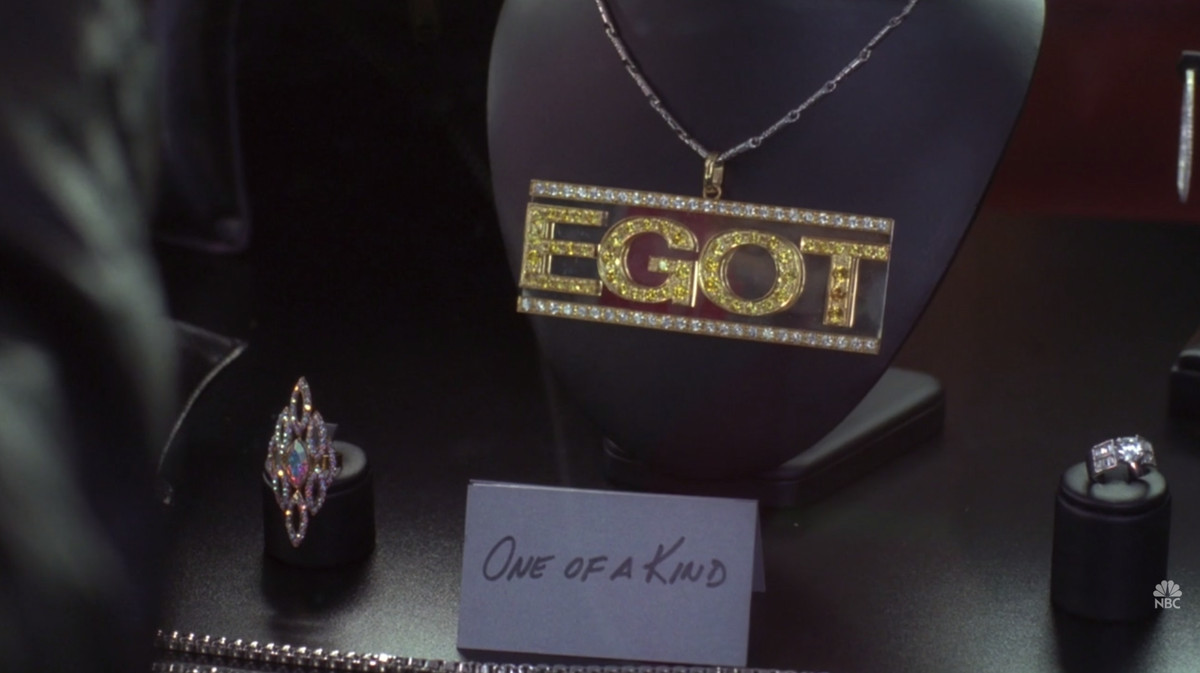 Image of the “EGOT” necklace in ‘30 Rock’ on a mannequin with a card in front reading “One of a kind” 